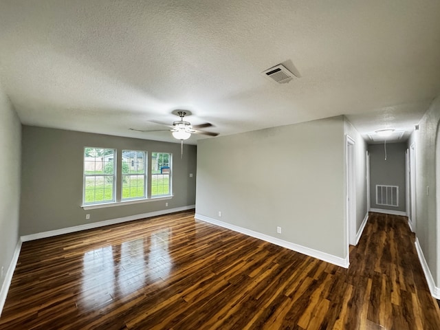 unfurnished room with attic access, dark wood-style floors, and visible vents
