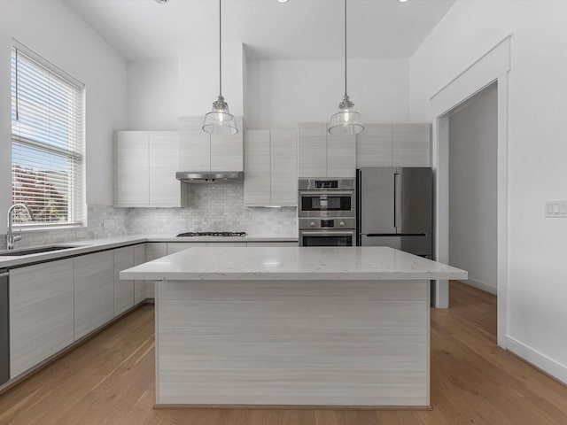 kitchen with a kitchen island, stainless steel appliances, a sink, and modern cabinets