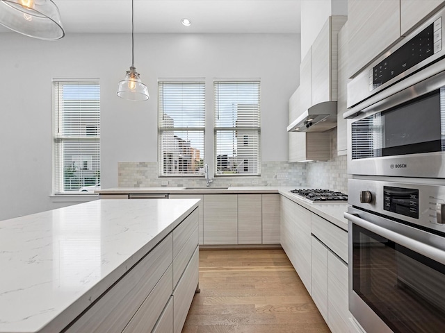 kitchen with backsplash, a sink, pendant lighting, and modern cabinets