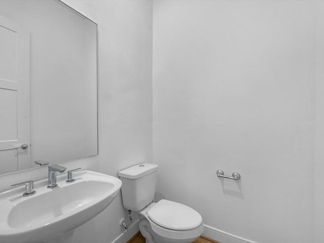 bathroom with toilet, baseboards, and a sink