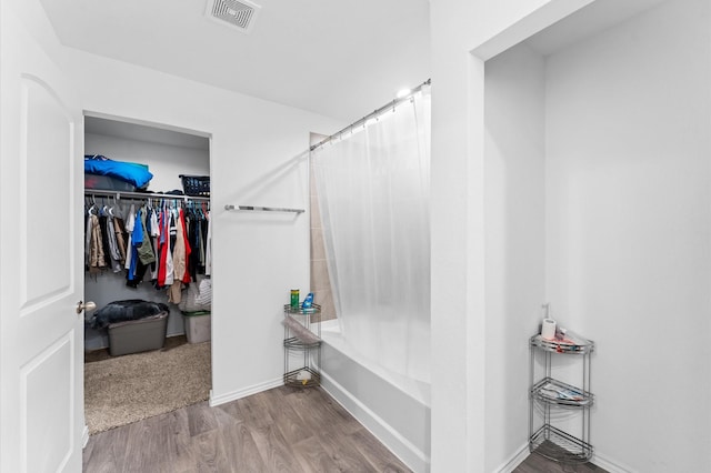 full bathroom featuring a walk in closet, visible vents, shower / bath combo, wood finished floors, and baseboards