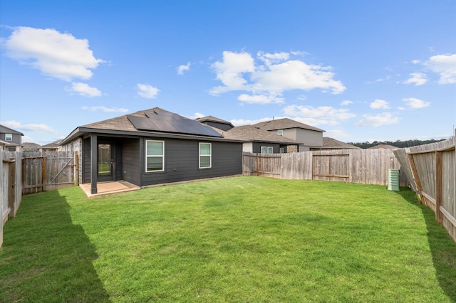 rear view of house featuring a lawn, a fenced backyard, and solar panels