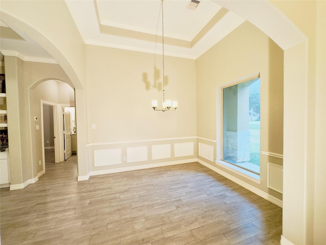 unfurnished dining area with light wood-style floors, visible vents, crown molding, arched walkways, and an inviting chandelier