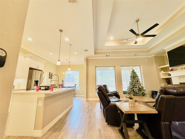 living room featuring crown molding, recessed lighting, light wood-type flooring, a raised ceiling, and a ceiling fan