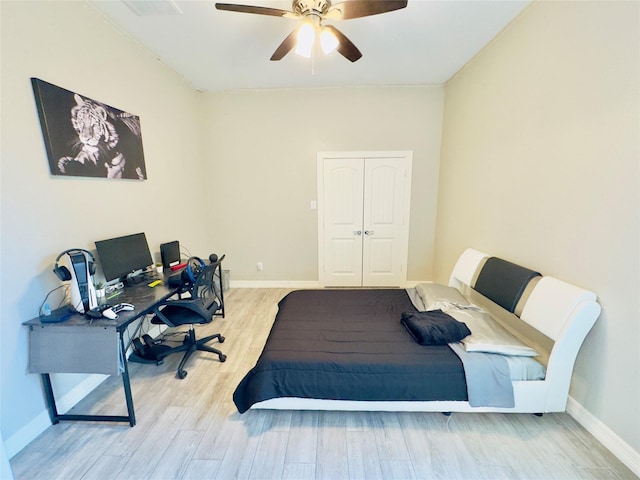 bedroom featuring baseboards, ceiling fan, wood finished floors, and a closet