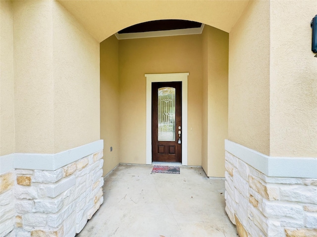 view of exterior entry with stucco siding and stone siding