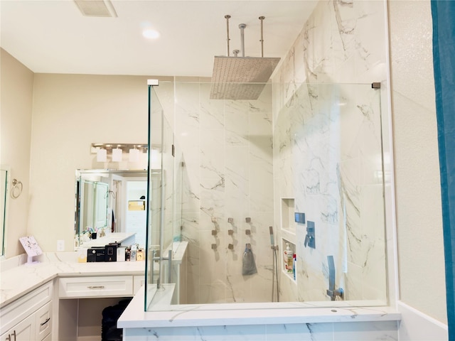 full bathroom with visible vents, a marble finish shower, and vanity