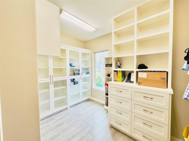 walk in closet with light wood-style floors