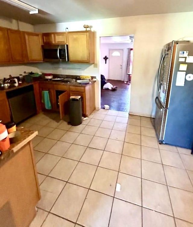 kitchen featuring brown cabinetry, appliances with stainless steel finishes, and light tile patterned floors