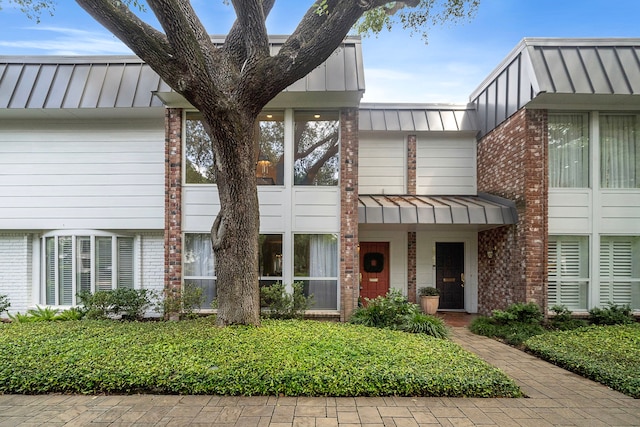 8944 Chatsworth Dr, Houston, TX 77024 - view of property with brick siding, a standing seam roof, and metal roof