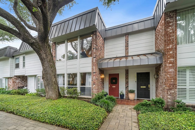8944 Chatsworth Dr, Houston, TX 77024 - view of front facade featuring board and batten siding, brick siding, a standing seam roof, and metal roof