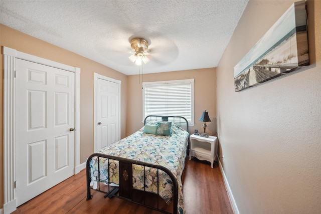 bedroom featuring baseboards, a textured ceiling, and wood finished floors