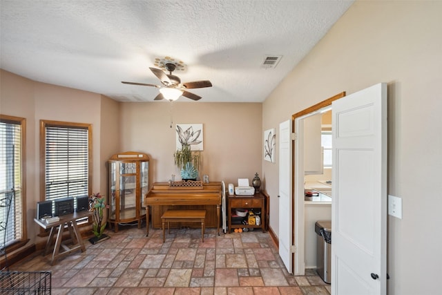 living area with visible vents, a ceiling fan, a textured ceiling, and baseboards