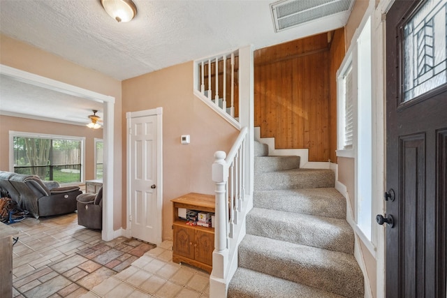 staircase with visible vents, baseboards, ceiling fan, stone finish floor, and a textured ceiling