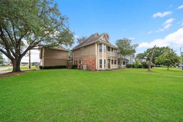back of property featuring brick siding, a lawn, and central air condition unit