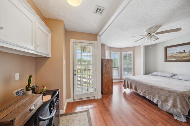 bedroom featuring access to outside, a textured ceiling, visible vents, and light wood-style flooring