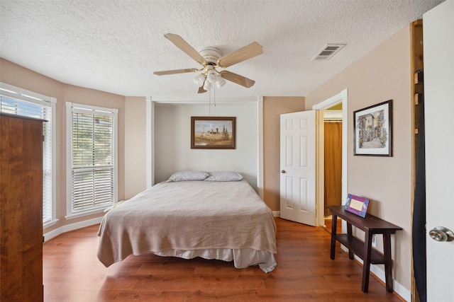 bedroom with visible vents, a textured ceiling, ceiling fan, and wood finished floors