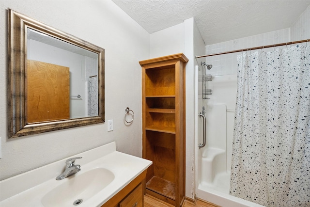 full bath with vanity, a textured ceiling, and a shower stall
