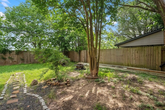 view of yard featuring a fenced backyard and a fire pit