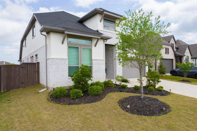 view of front of home featuring driveway, brick siding, fence, a front lawn, and stucco siding