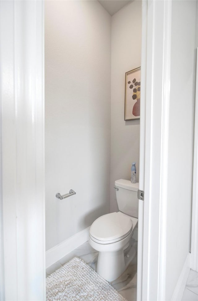 bathroom with baseboards, marble finish floor, and toilet