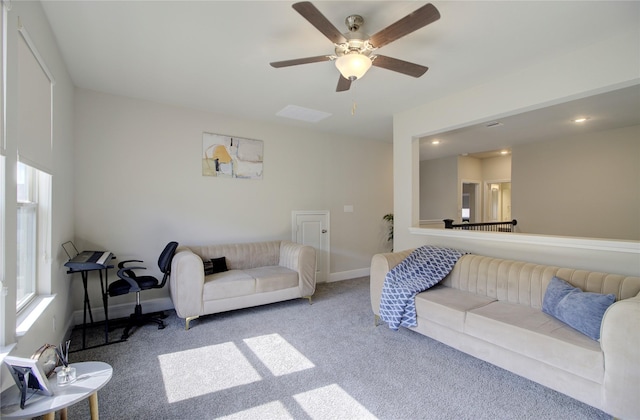 living area with baseboards, carpet, a ceiling fan, and a wealth of natural light