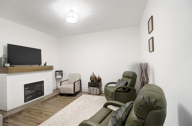 living room featuring baseboards, a glass covered fireplace, and wood finished floors