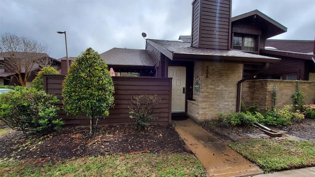 exterior space featuring brick siding, fence, and a chimney