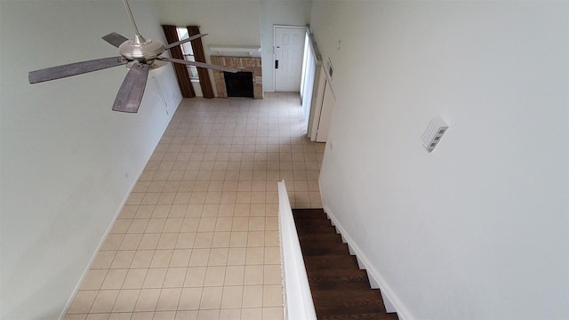 stairway with baseboards, a ceiling fan, tile patterned floors, and a fireplace