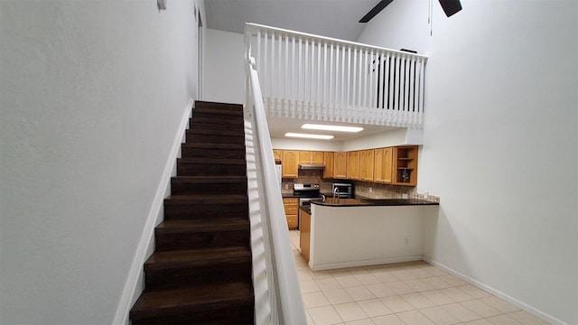 stairway with baseboards, ceiling fan, and tile patterned flooring