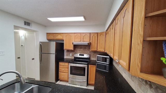 kitchen featuring visible vents, under cabinet range hood, a sink, appliances with stainless steel finishes, and backsplash