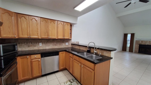 kitchen featuring appliances with stainless steel finishes, tasteful backsplash, vaulted ceiling, a sink, and a peninsula