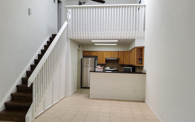 2611 Grants Lake Blvd Unit 228, Sugar Land, TX 77479 - kitchen with stainless steel appliances, a high ceiling, dark countertops, tasteful backsplash, and under cabinet range hood
