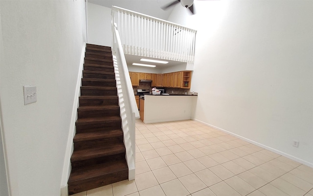 2611 Grants Lake Blvd Unit 228, Sugar Land, TX 77479 - stairway featuring a ceiling fan, tile patterned floors, a towering ceiling, and baseboards