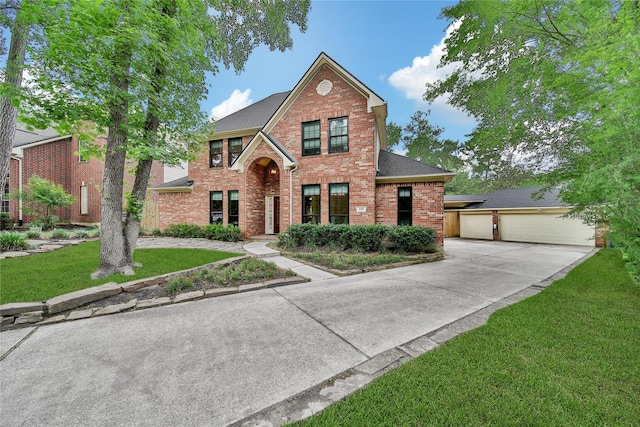 traditional-style house with a shingled roof, a front yard, driveway, and brick siding