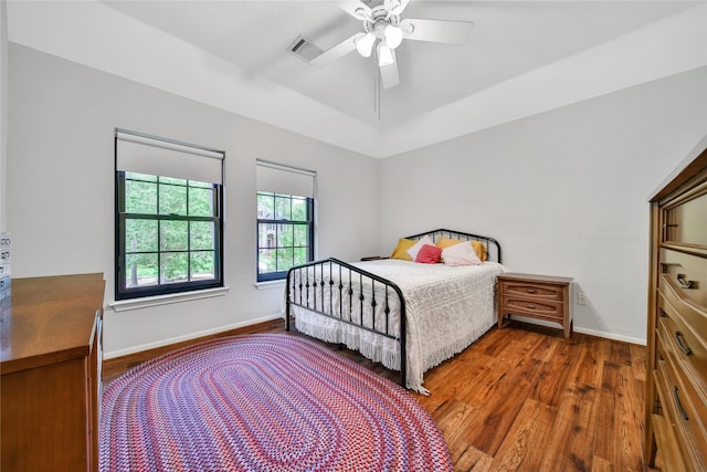bedroom with baseboards, ceiling fan, wood finished floors, and visible vents