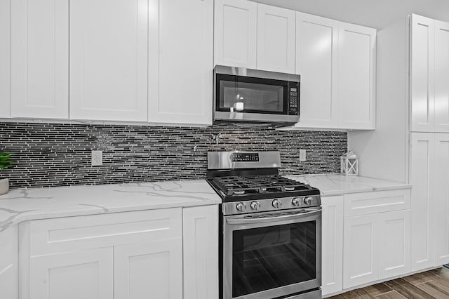 3409 2nd Ave N, Texas City, TX 77590 - kitchen featuring light stone counters, white cabinetry, tasteful backsplash, and stainless steel appliances