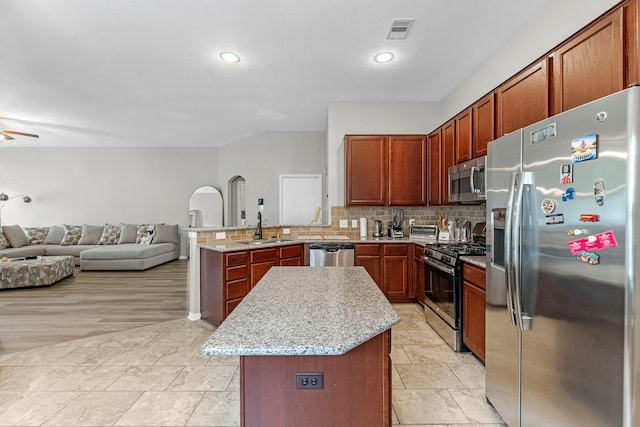 kitchen featuring a sink, stainless steel appliances, open floor plan, a peninsula, and visible vents