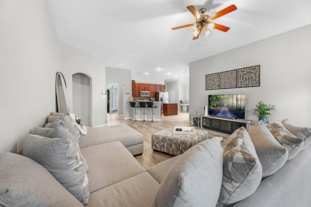 living area featuring arched walkways, ceiling fan, recessed lighting, and light wood-style floors