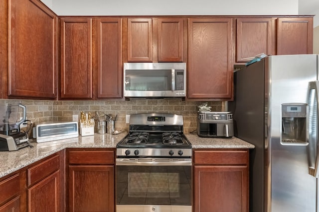 kitchen with backsplash, a toaster, light stone countertops, and stainless steel appliances