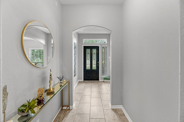 entrance foyer featuring light tile patterned flooring, baseboards, and a healthy amount of sunlight