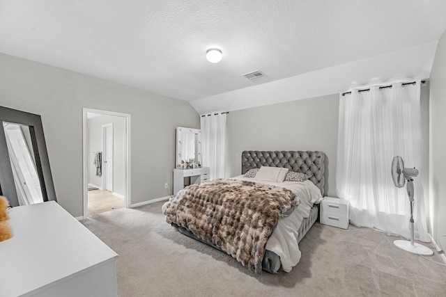 bedroom featuring visible vents, lofted ceiling, baseboards, light colored carpet, and a textured ceiling