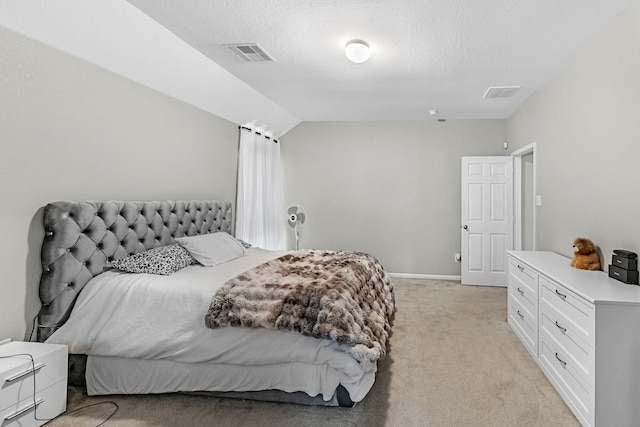 bedroom featuring a textured ceiling, visible vents, light carpet, and vaulted ceiling