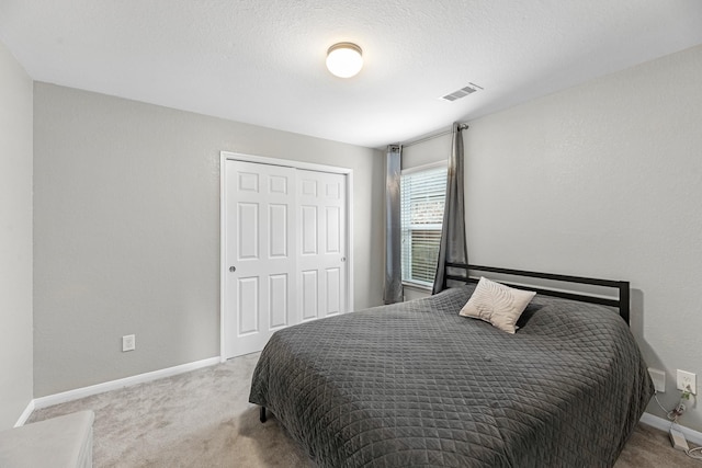 carpeted bedroom featuring baseboards, visible vents, and a closet