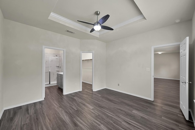 4202 Amber Ruse Dr, Conroe, TX 77304 - unfurnished bedroom with dark wood-type flooring, visible vents, a walk in closet, a raised ceiling, and baseboards