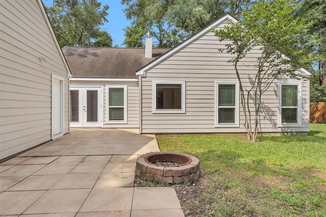 91 Bitterwood Cir, The Woodlands, TX 77381 - rear view of house with a chimney, roof with shingles, a lawn, a patio area, and an outdoor fire pit