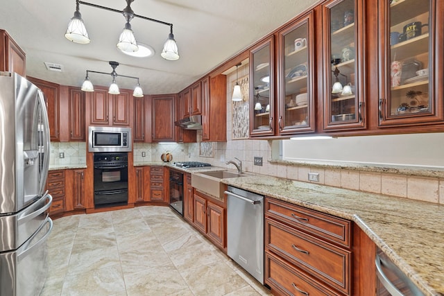 28710 Sapphire Cir, Magnolia, TX 77355 - kitchen with appliances with stainless steel finishes, decorative backsplash, under cabinet range hood, light stone countertops, and a sink