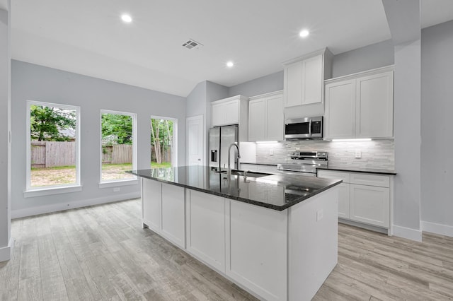 12390 Green Ridge Dr, Willis, TX 77318 - kitchen with white cabinets, stainless steel appliances, a sink, and tasteful backsplash