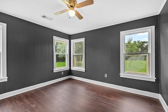 empty room featuring baseboards, a ceiling fan, dark wood-style flooring, and visible vents