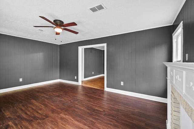 unfurnished room with visible vents, wood finished floors, a fireplace, baseboards, and ceiling fan